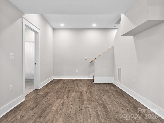 below grade area with dark wood-style flooring, baseboards, recessed lighting, and stairway