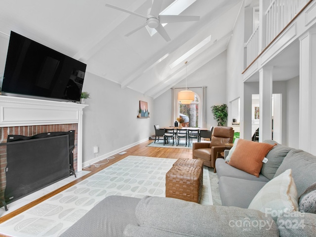 living room with a brick fireplace, hardwood / wood-style floors, ceiling fan, and high vaulted ceiling