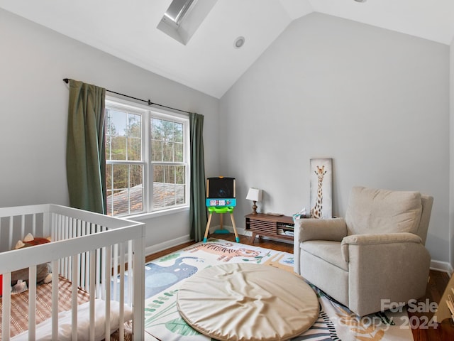 bedroom with a crib, high vaulted ceiling, and hardwood / wood-style flooring