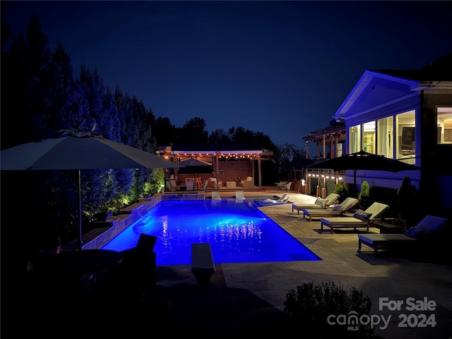 pool at twilight with a patio area