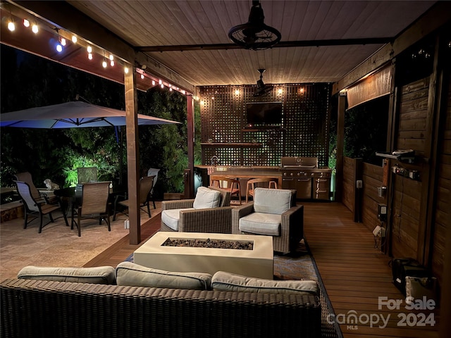 view of patio with a wooden deck, ceiling fan, area for grilling, and an outdoor fire pit