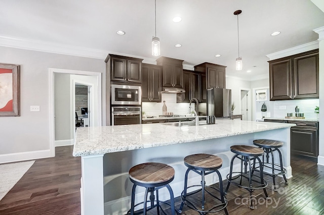 kitchen featuring a large island with sink, stainless steel appliances, and tasteful backsplash