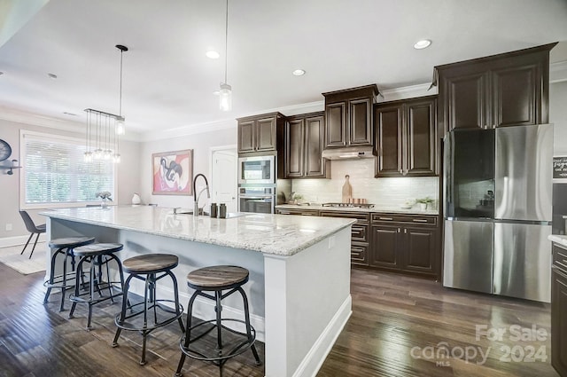 kitchen with hanging light fixtures, stainless steel appliances, a kitchen breakfast bar, dark hardwood / wood-style flooring, and a spacious island