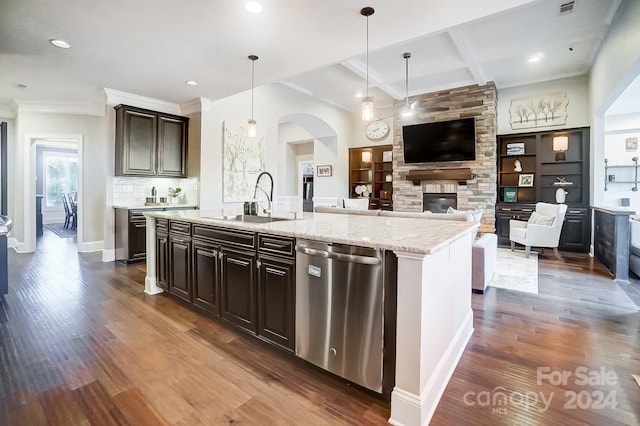 kitchen with stainless steel dishwasher, dark wood-type flooring, sink, decorative light fixtures, and a center island with sink