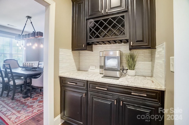 bar featuring hardwood / wood-style floors, dark brown cabinetry, and backsplash