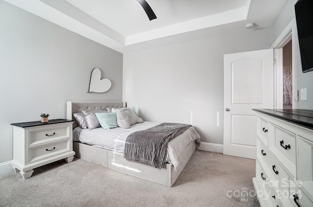 carpeted bedroom with ceiling fan and a tray ceiling