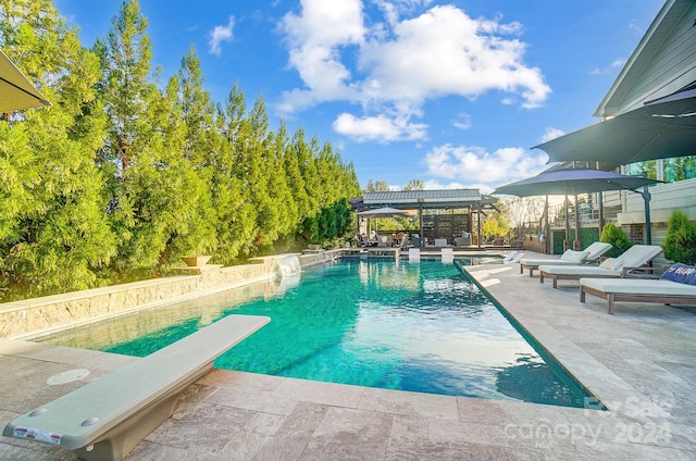 view of swimming pool with a patio area and a diving board