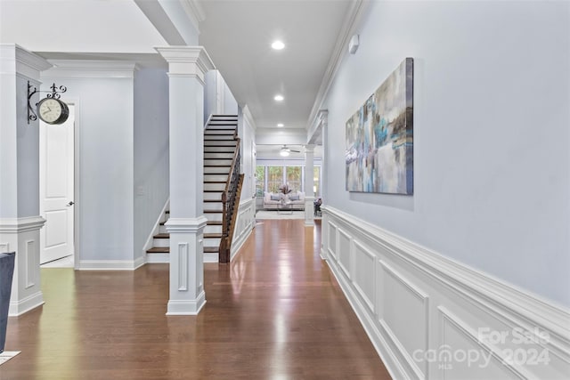 hall with ornamental molding, decorative columns, and dark wood-type flooring