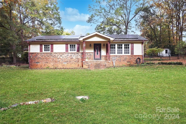 ranch-style house with covered porch, solar panels, and a front yard