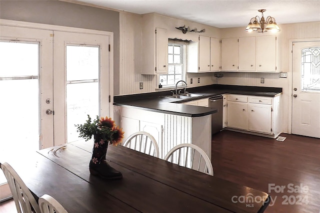 kitchen with decorative light fixtures, white cabinets, dark wood-type flooring, stainless steel dishwasher, and a chandelier