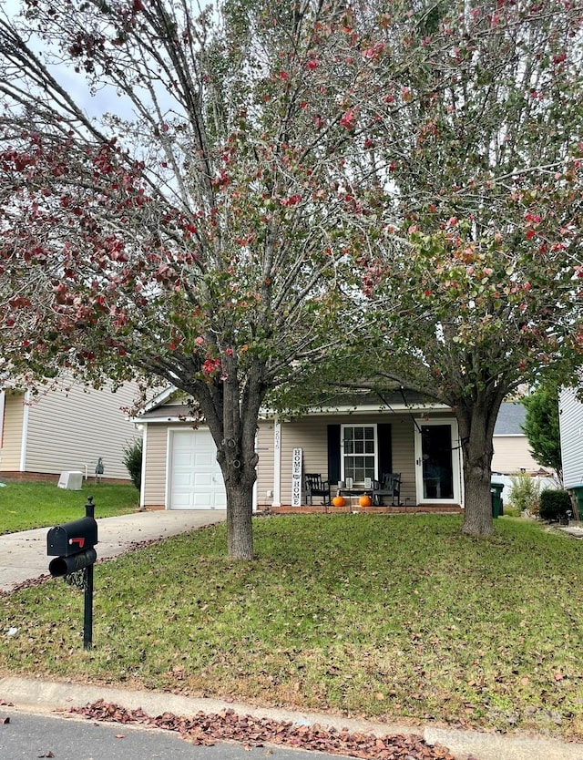 view of property hidden behind natural elements featuring a garage and a front lawn