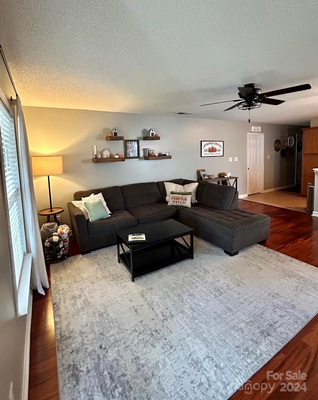 living room featuring hardwood / wood-style floors, ceiling fan, and a textured ceiling