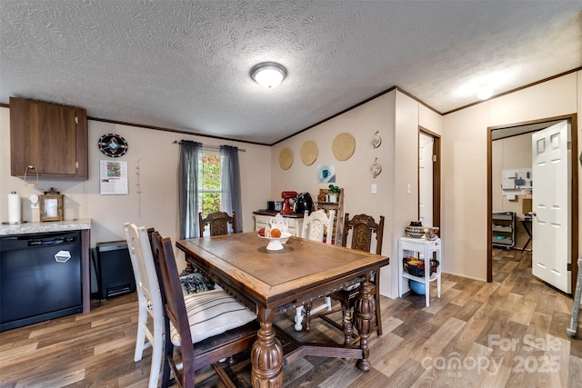 dining room with a textured ceiling, wood-type flooring, and ornamental molding