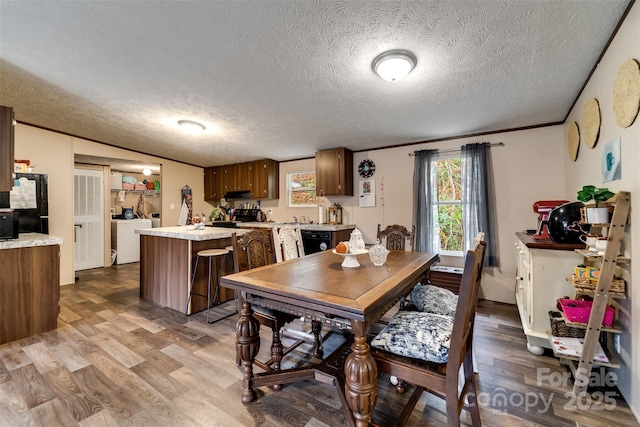 dining room featuring wood-type flooring, a textured ceiling, separate washer and dryer, and ornamental molding