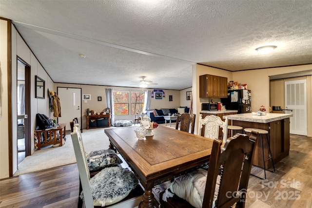 dining area with ceiling fan, crown molding, dark wood-type flooring, and a textured ceiling