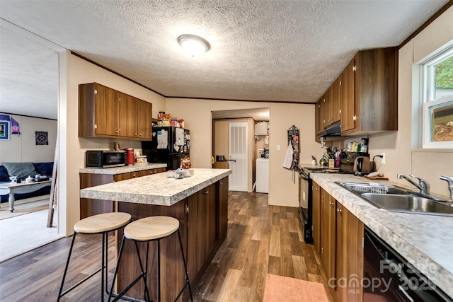 kitchen with dark wood-type flooring, exhaust hood, black appliances, sink, and a textured ceiling