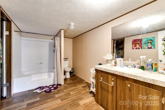 bathroom with a shower with curtain, vanity, a textured ceiling, wood-type flooring, and toilet