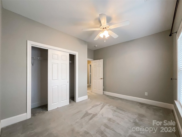 unfurnished bedroom with light colored carpet, ceiling fan, and a closet