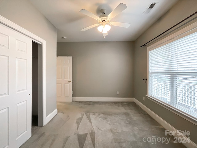 unfurnished bedroom featuring ceiling fan, light carpet, and a closet