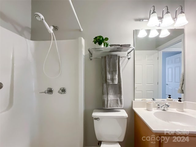 bathroom with toilet, a shower, and vanity