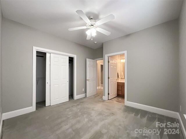 unfurnished bedroom featuring connected bathroom, a closet, carpet flooring, and ceiling fan