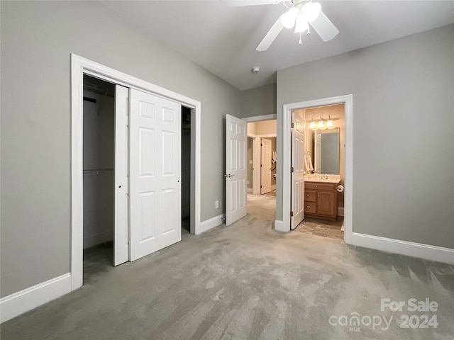 unfurnished bedroom featuring ensuite bathroom, ceiling fan, a closet, and light colored carpet