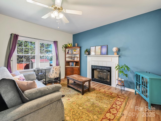 living room with ceiling fan, a fireplace, and wood-type flooring