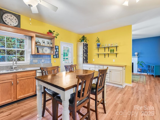 dining space featuring light wood-type flooring, ceiling fan, and sink