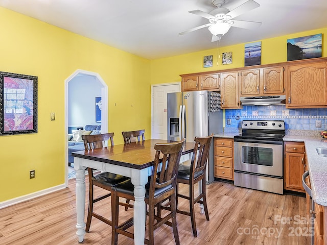 kitchen featuring backsplash, ceiling fan, light wood-type flooring, and stainless steel appliances