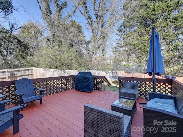 wooden deck with a grill and a trampoline