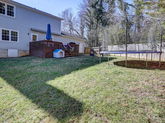 view of yard featuring a trampoline and a wooden deck