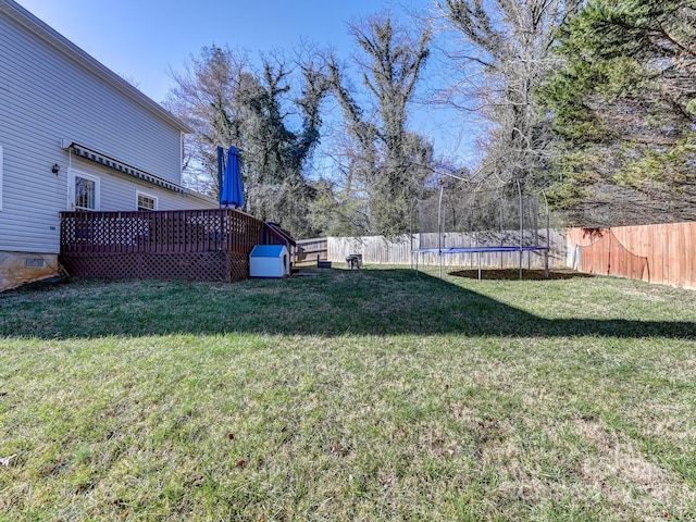 view of yard with a trampoline and a wooden deck