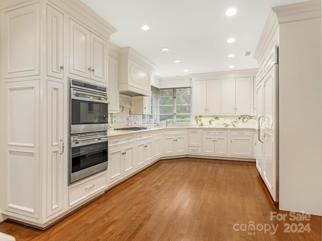 kitchen featuring white cabinets, light hardwood / wood-style flooring, decorative backsplash, stainless steel double oven, and gas cooktop