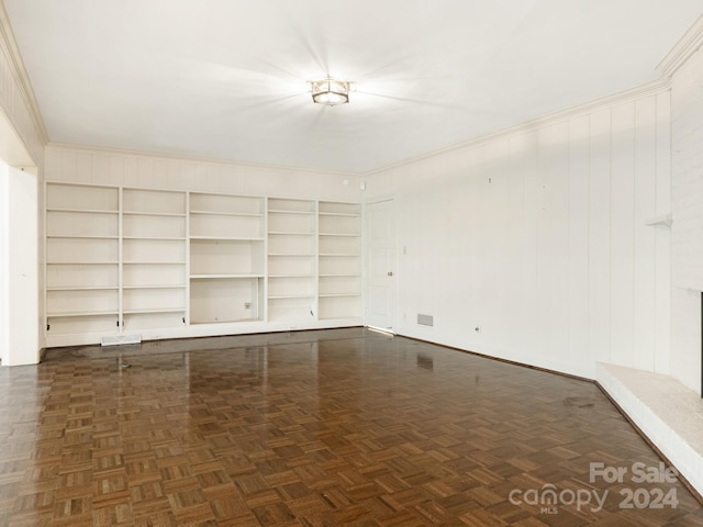 spare room featuring dark parquet floors, built in features, crown molding, and wooden walls