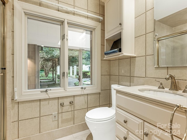 bathroom featuring walk in shower, tile patterned floors, toilet, vanity, and tile walls