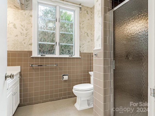 bathroom featuring walk in shower, vanity, toilet, and tile walls