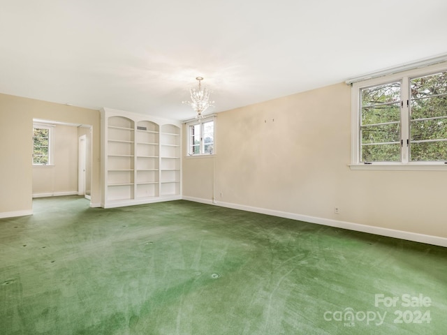 carpeted spare room with a wealth of natural light and a chandelier