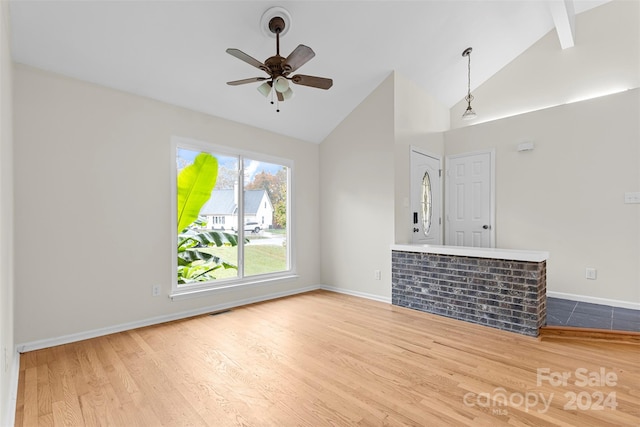 unfurnished living room with hardwood / wood-style floors, beamed ceiling, high vaulted ceiling, and ceiling fan