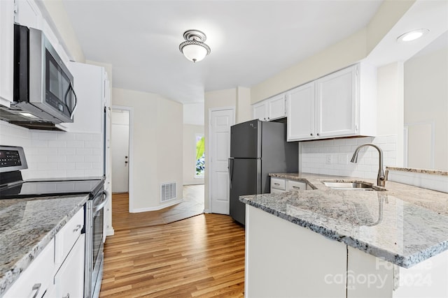 kitchen featuring kitchen peninsula, sink, white cabinetry, light wood-type flooring, and appliances with stainless steel finishes