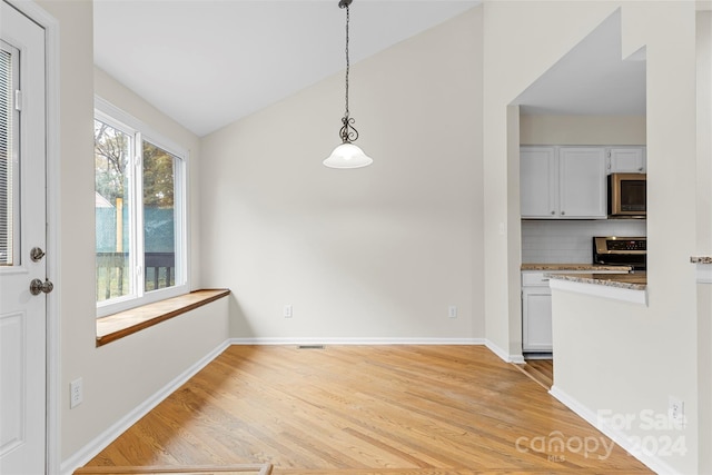 unfurnished dining area featuring light hardwood / wood-style flooring and lofted ceiling