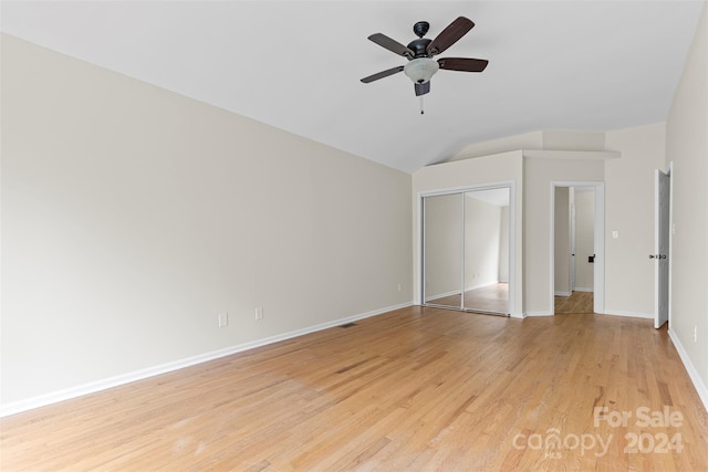 unfurnished bedroom featuring light wood-type flooring, ceiling fan, vaulted ceiling, and a closet