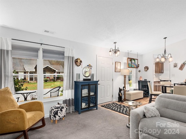 living room featuring a textured ceiling, carpet floors, and a chandelier