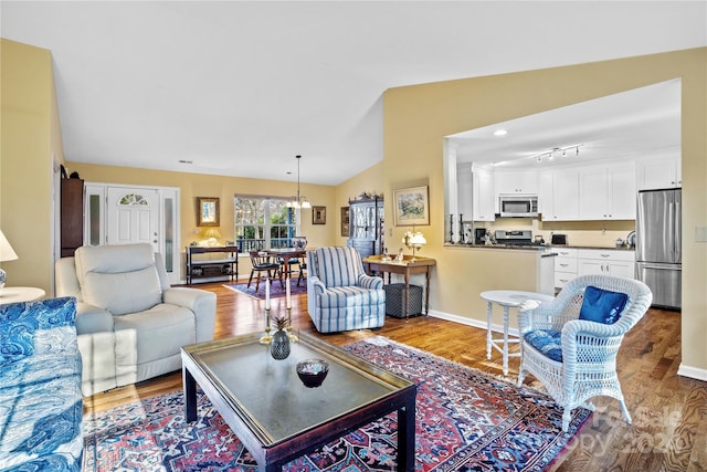 living room featuring light hardwood / wood-style floors, lofted ceiling, and a notable chandelier