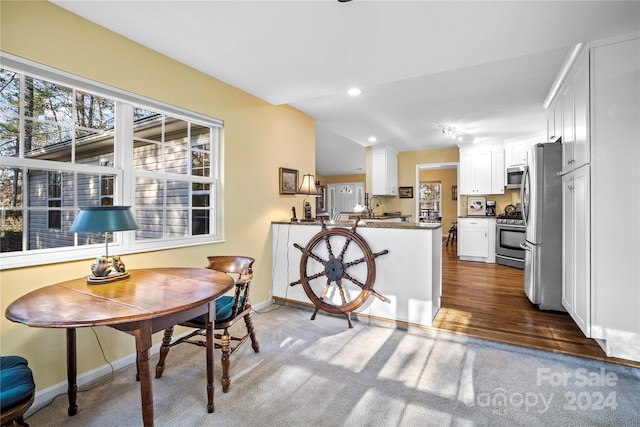 kitchen featuring stainless steel appliances, white cabinetry, sink, kitchen peninsula, and dark wood-type flooring