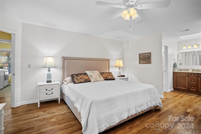 bedroom with light hardwood / wood-style floors, ceiling fan, ensuite bath, and sink