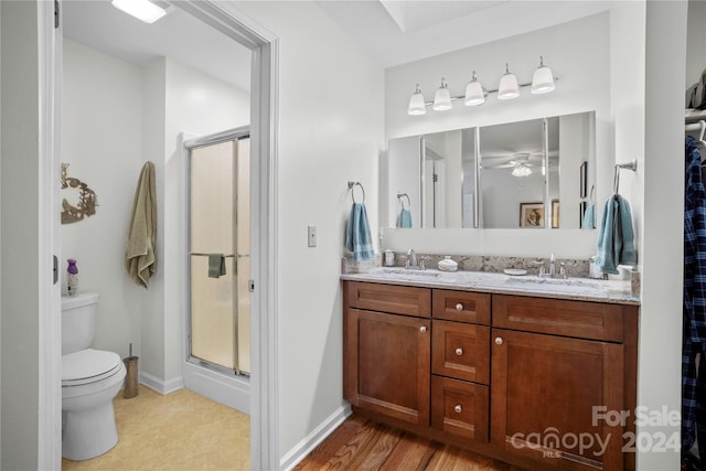 bathroom featuring vanity, an enclosed shower, hardwood / wood-style flooring, toilet, and ceiling fan