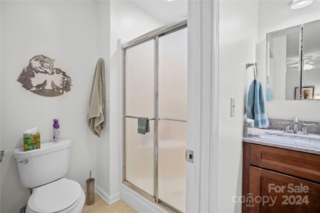 bathroom featuring toilet, vanity, tile patterned floors, and a shower with shower door