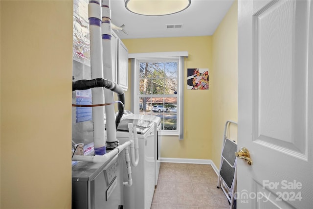 washroom with washing machine and clothes dryer and light tile patterned floors