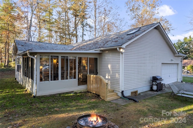 rear view of house featuring a garage and a sunroom