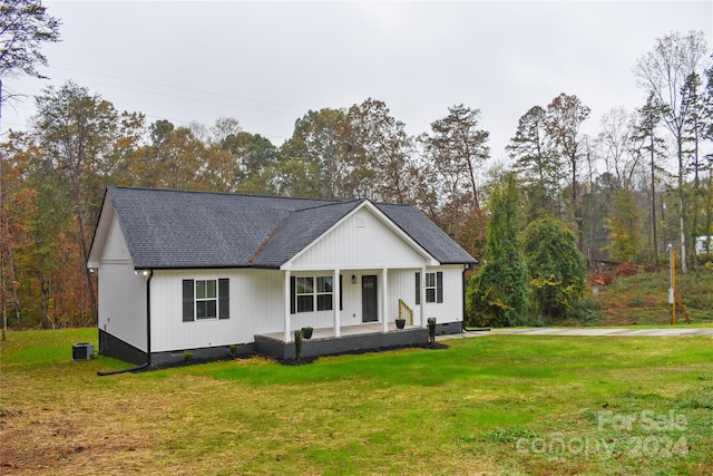 view of front of house with covered porch, a front yard, and central AC